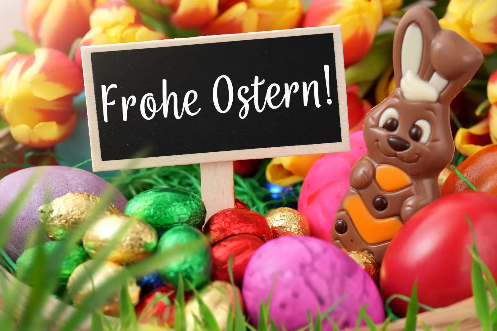 Osternest mit bunten eiern, frühlingsblumen und osterhasen