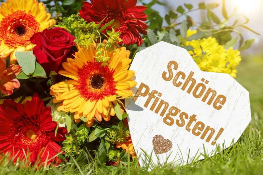 Schöne pfingsten wünsche mit blumenstrauß und herzschild