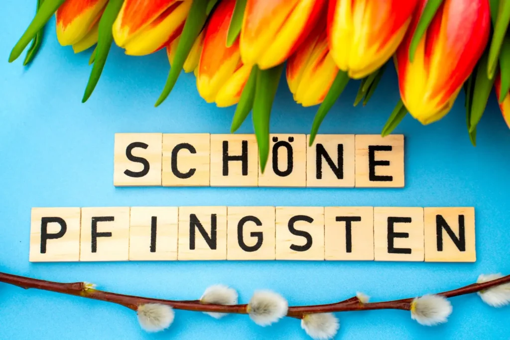 Schöne pfingsten wünsche mit tulpen und holzbuchstaben auf blau