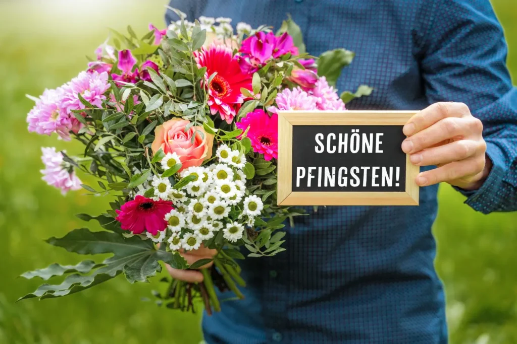 Schöne pfingsten wünschen mit blumenstrauß und tafel in der hand