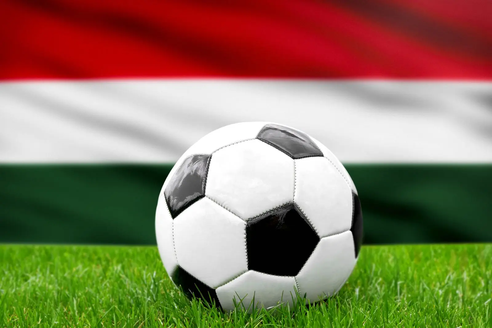 Ein fußball vor der ungarischen fahne symbolisiert die nationalmannschaft von ungarn im fußball.