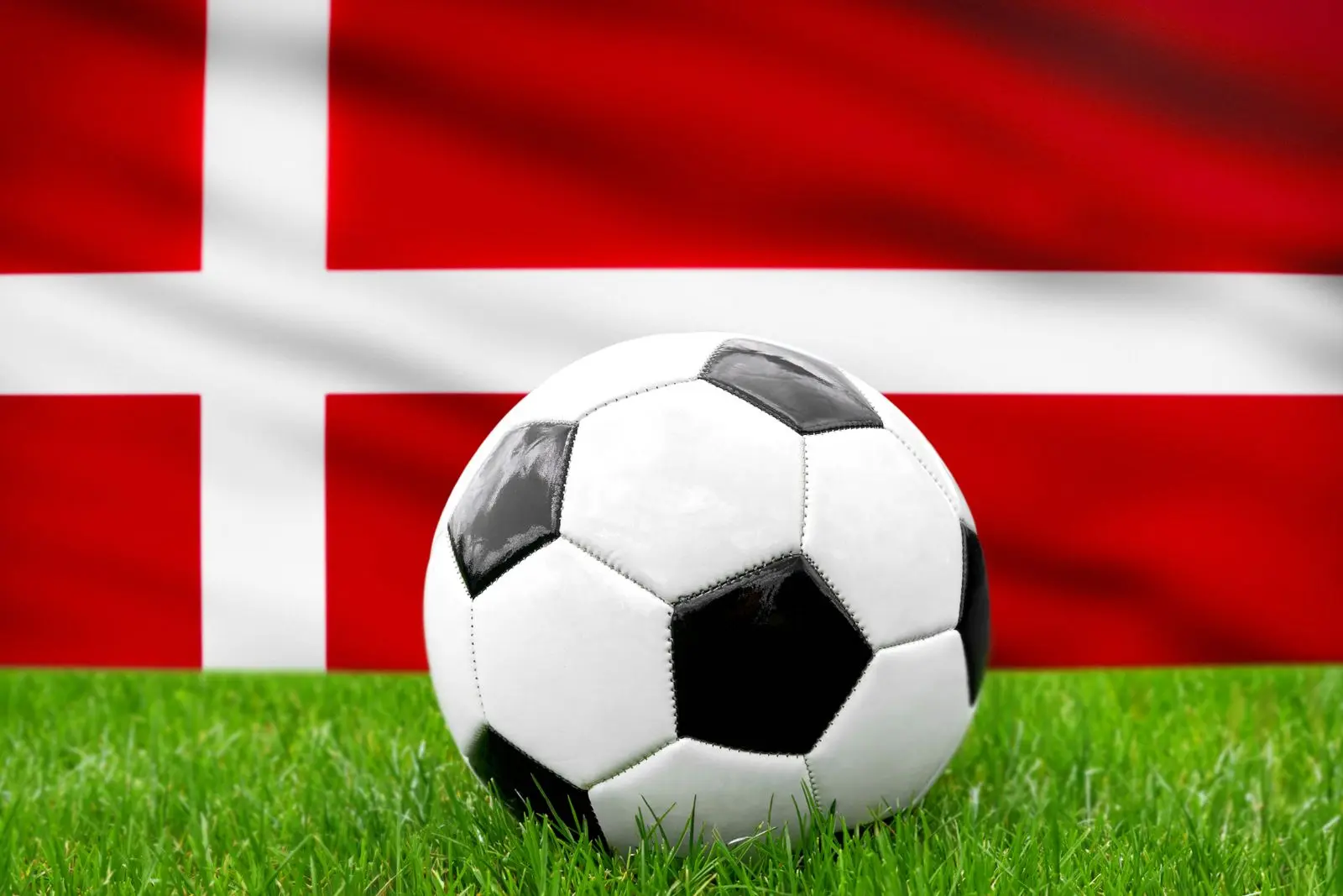 Fußball vor der dänemark-fahne, symbolisierend die dänische nationalmannschaft und den fußball.
