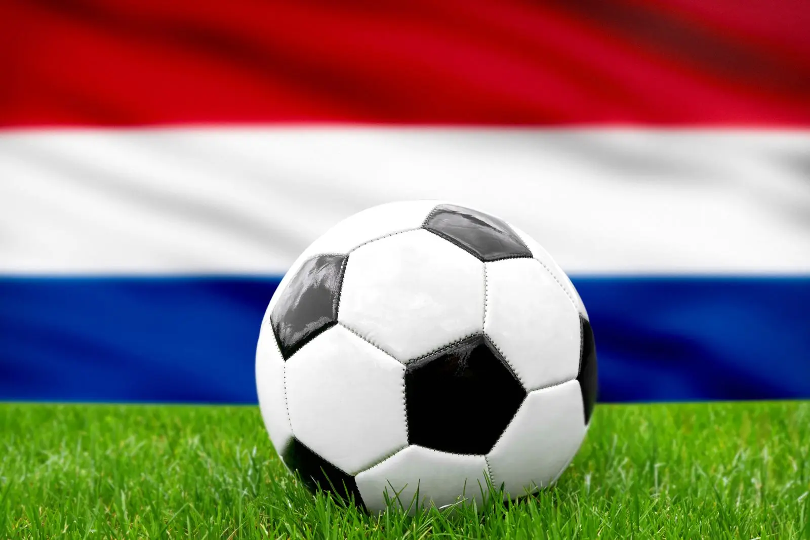 Fußball vor der niederlande-fahne, symbolisierend die niederländische nationalmannschaft und den fußball.