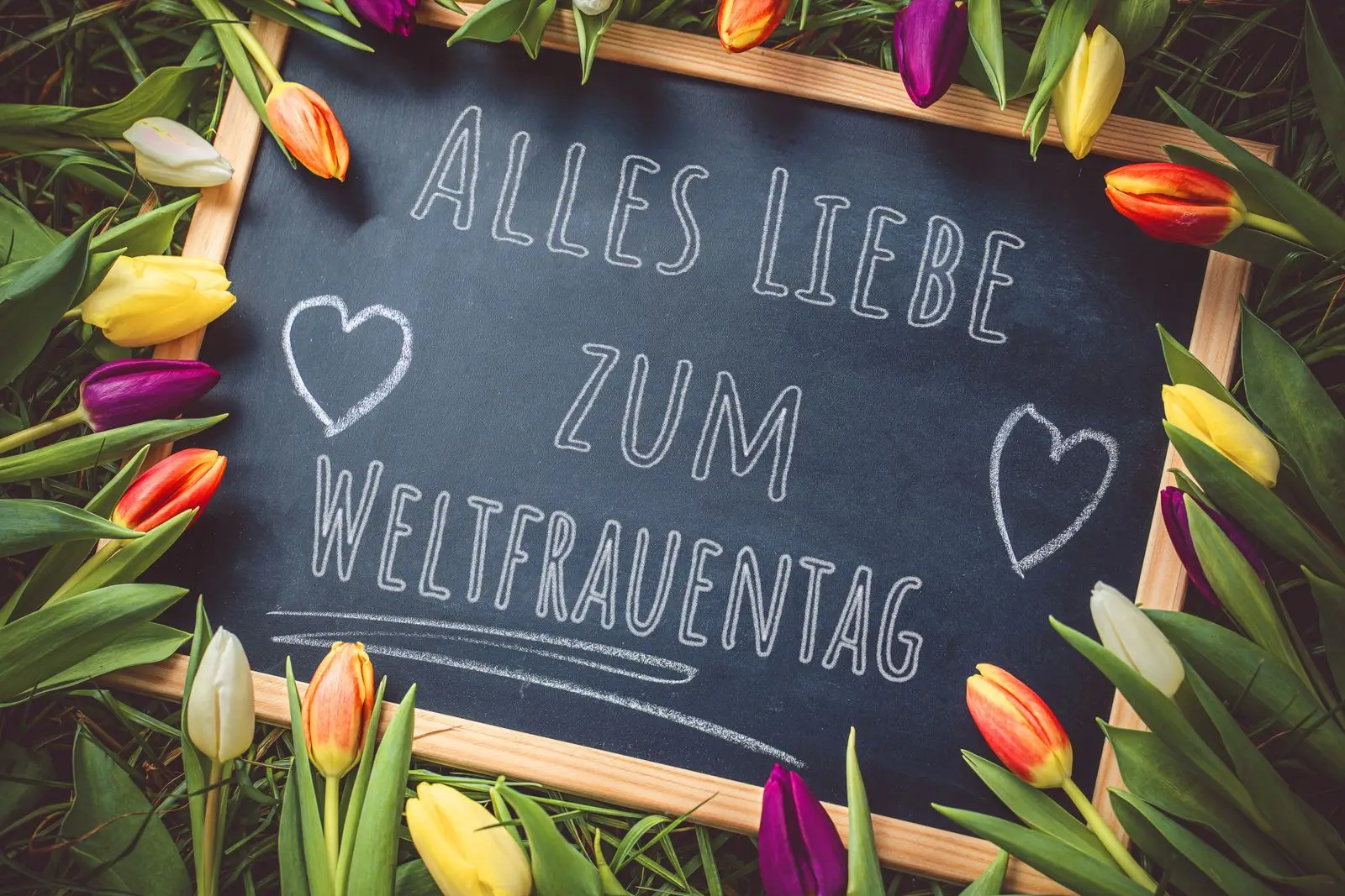 Spruche zum frauentag auf tafel neben tulpen und herz