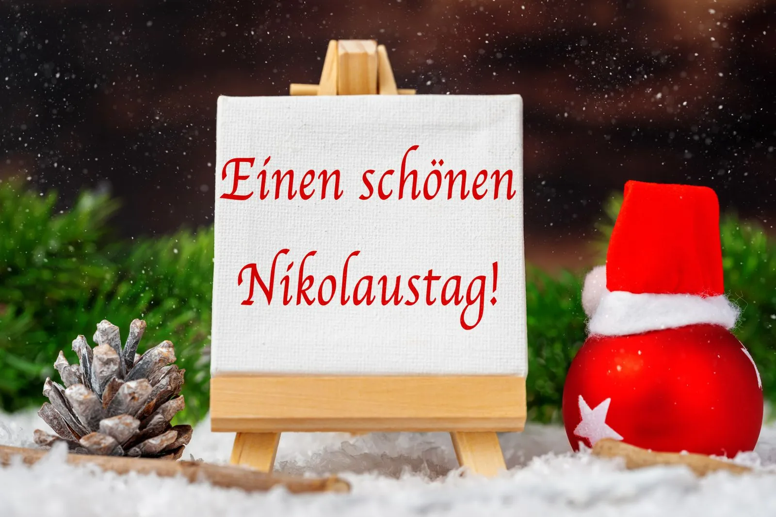 Einen schönen nikolaustag! Auf leinwand mit nikolausdeko im schnee mit mütze vom nikolaus.