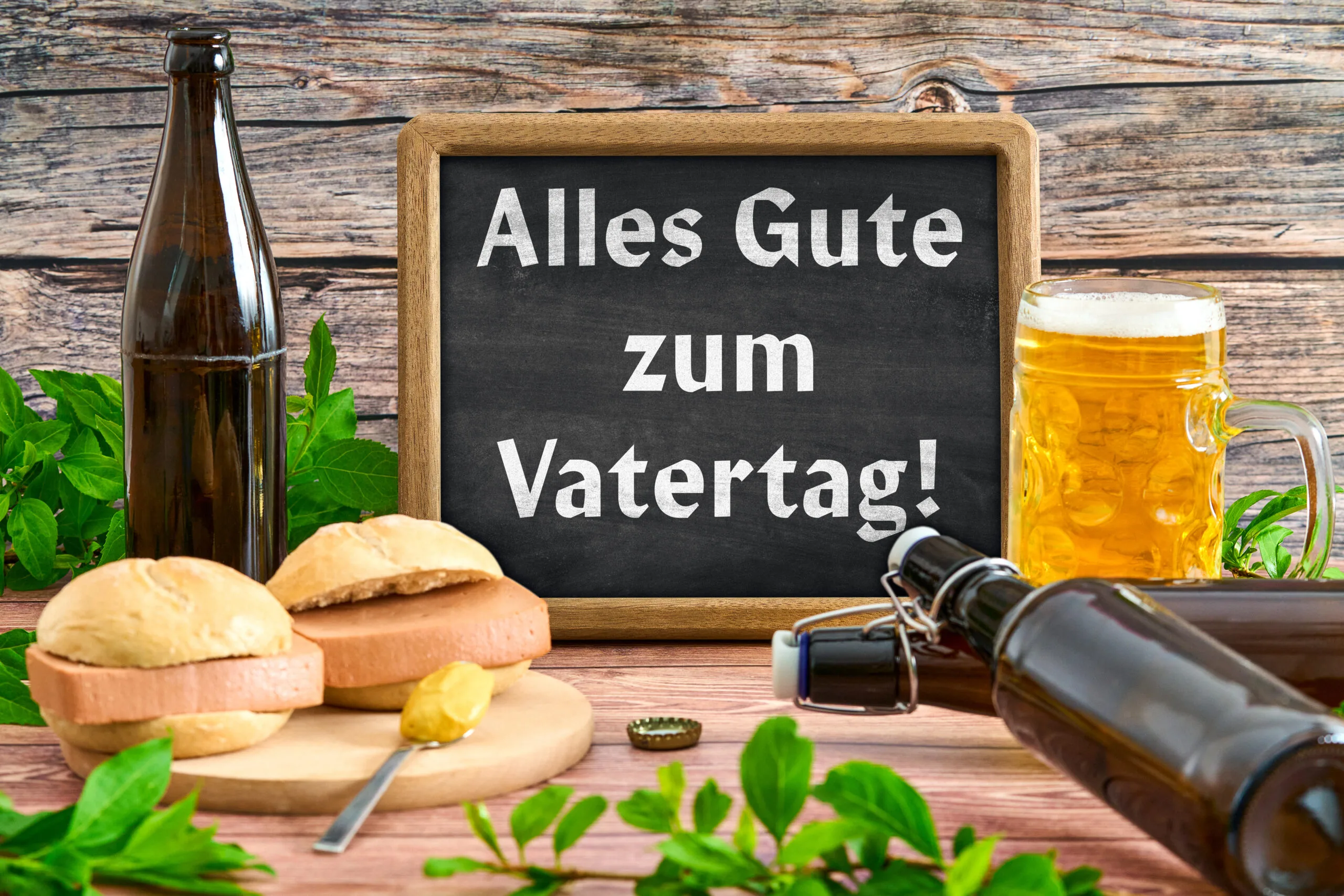 Tafel mit aufschrift ‚alles gute zum vatertag‘ neben bier und burgern auf einem holztisch