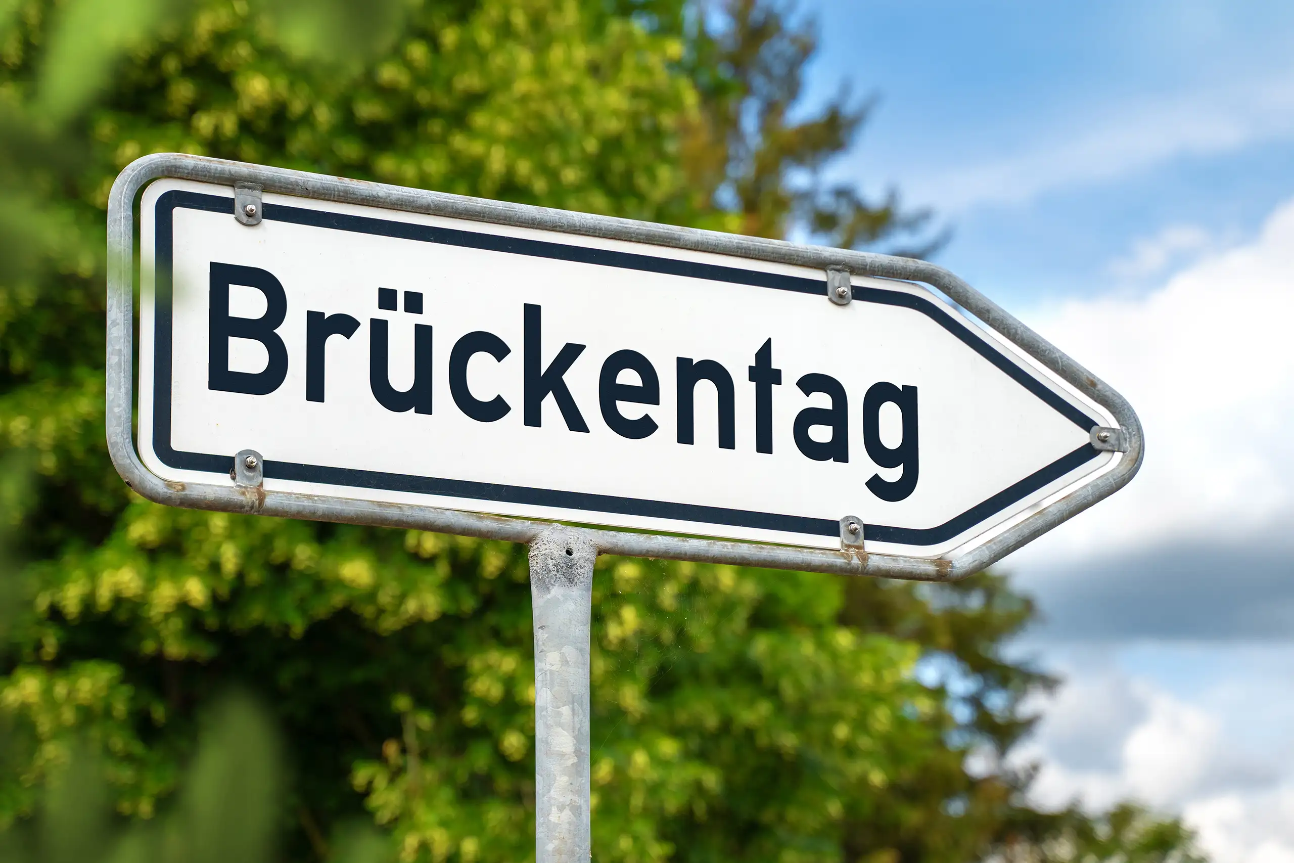 Wegweiser mit schriftzug brückentag in ländlicher umgebung als symbol für verlängertes wochenende