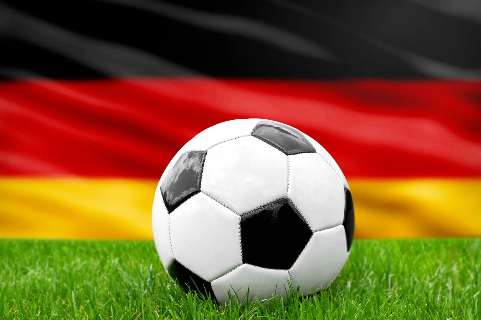Deutschland gegen gegner im fußballspiel mit fußball vor deutscher flagge als symbol für ein länderspiel der nationalelf