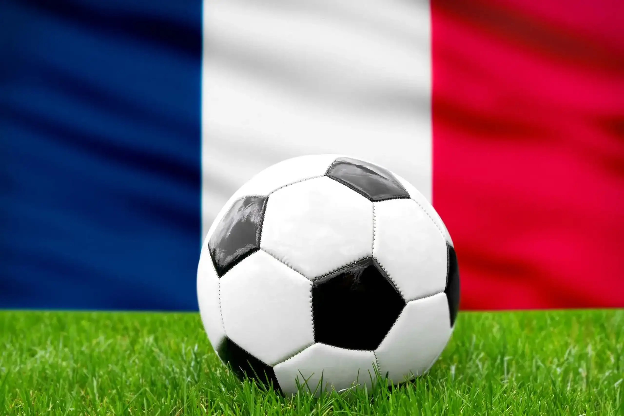 Frankreich fußball nationalmannschaft mit fußball vor französischer flagge auf grünem rasen