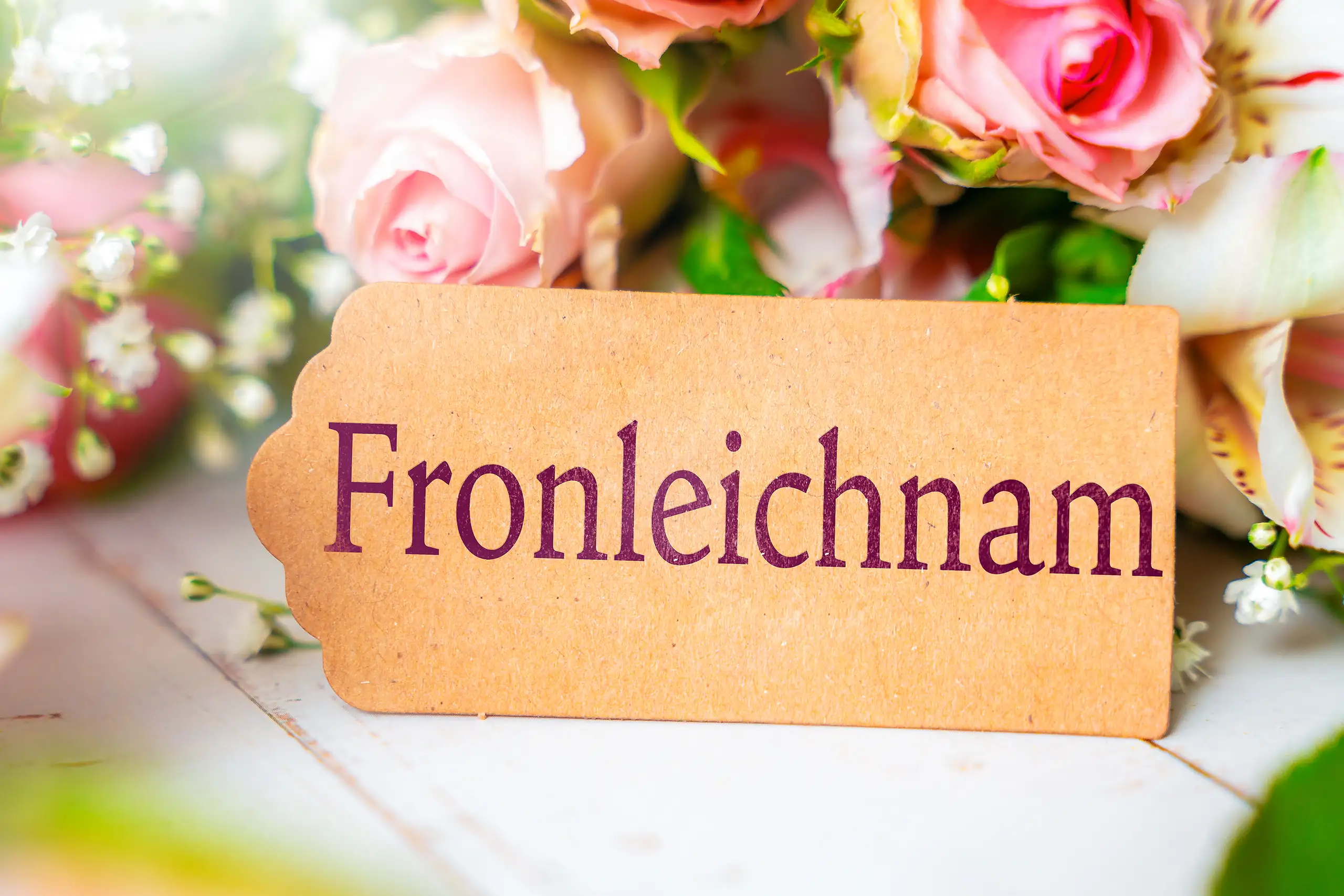 Schild mit fronleichnam spruch vor blumen