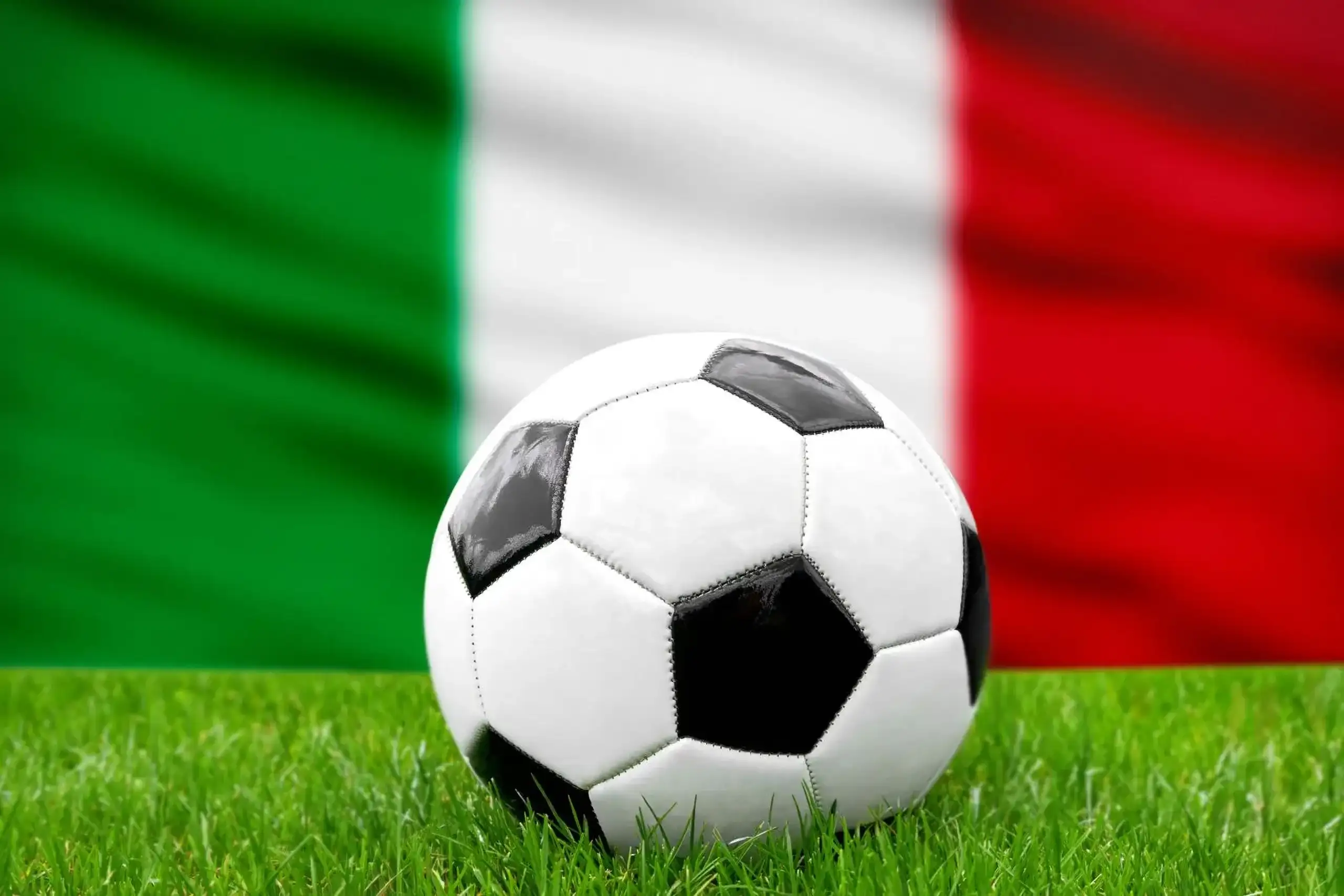 Italien fußball nationalmannschaft mit fußball vor italienischer flagge auf grünem rasen