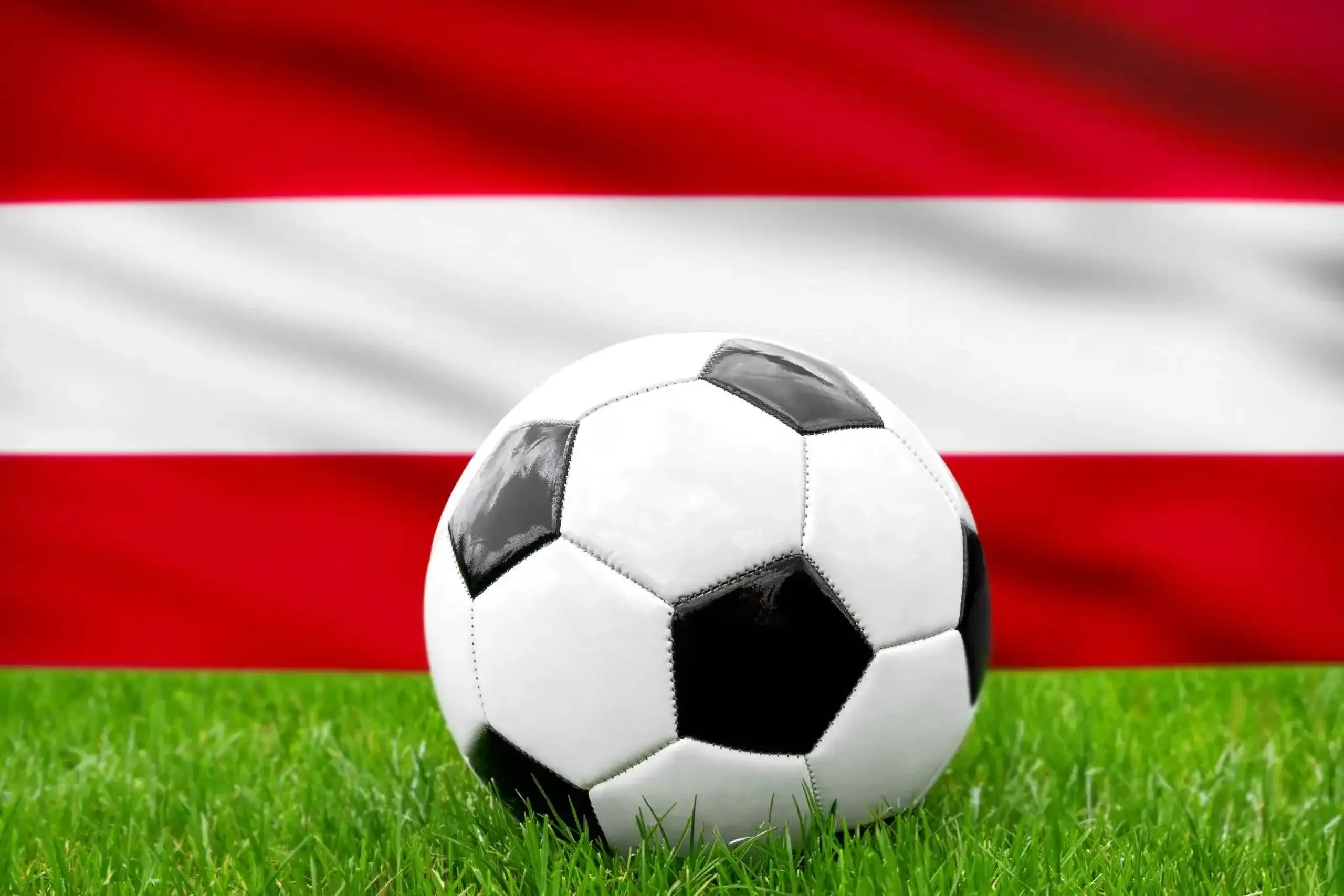 Österreich fußball nationalmannschaft mit fußball vor österreicher flagge auf grünem rasen