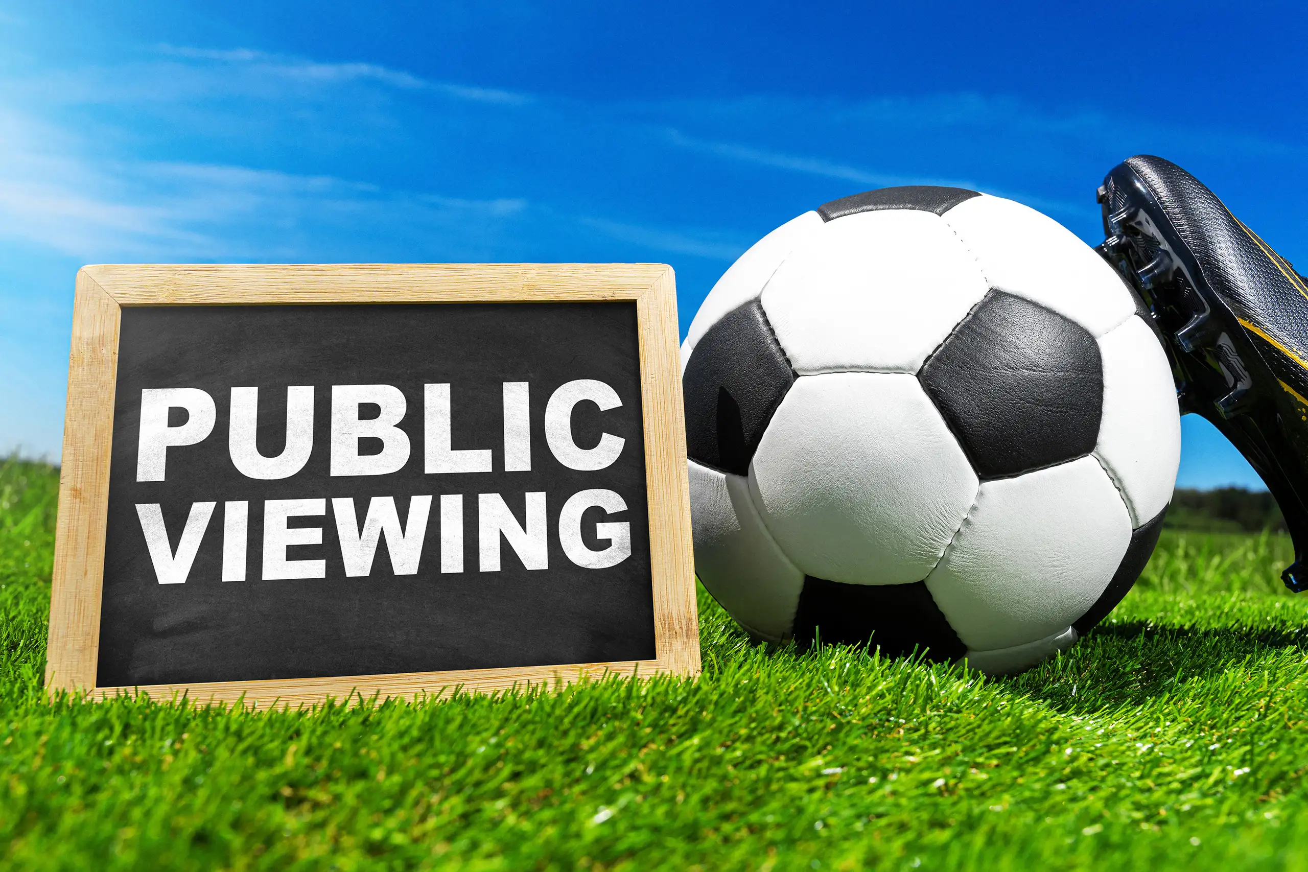 Public viewing mit fußball und fußballschuh auf dem sportplatz als symbol für liveübertragungen und fanveranstaltungen.