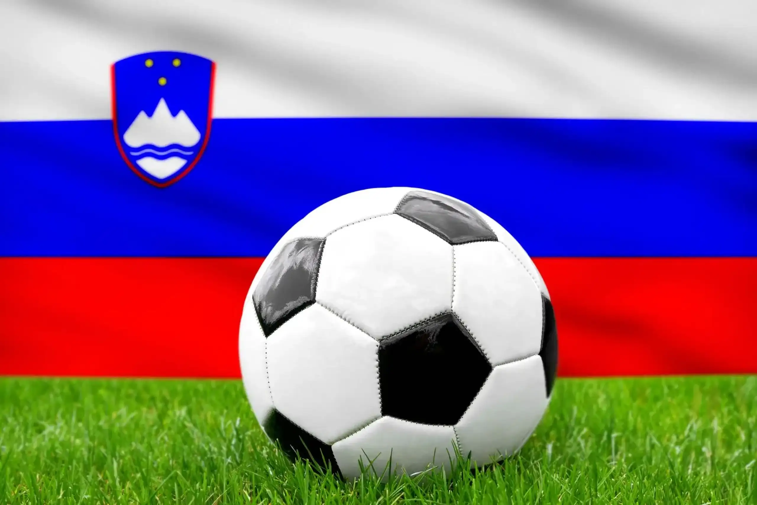 Slowenien fußball nationalmannschaft mit fußball vor slowenischer flagge auf grünem rasen