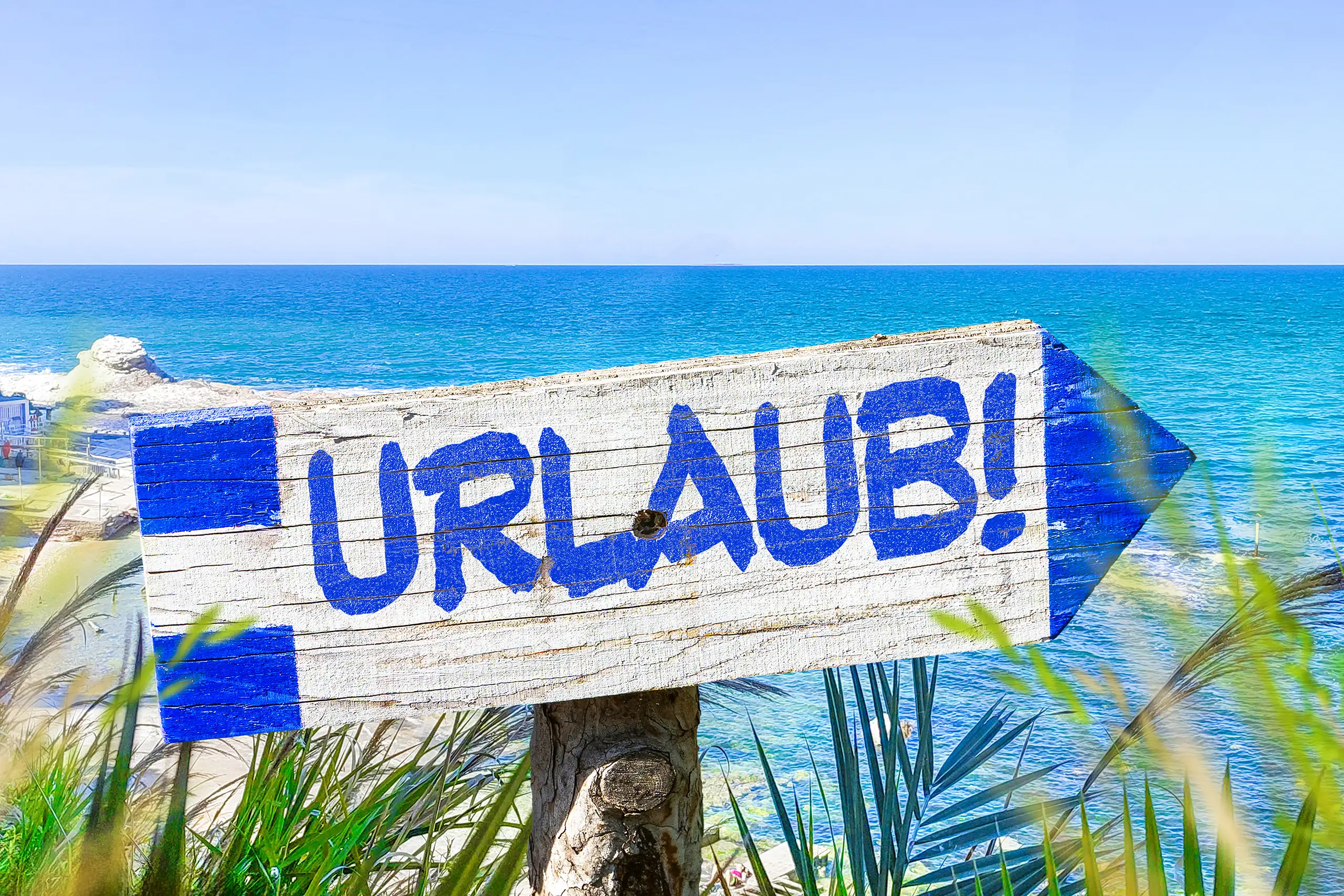 Urlaub schild am meer mit blauem schriftzug und pfeil vor sonniger küstenlandschaft als symbol für ferien und erholung