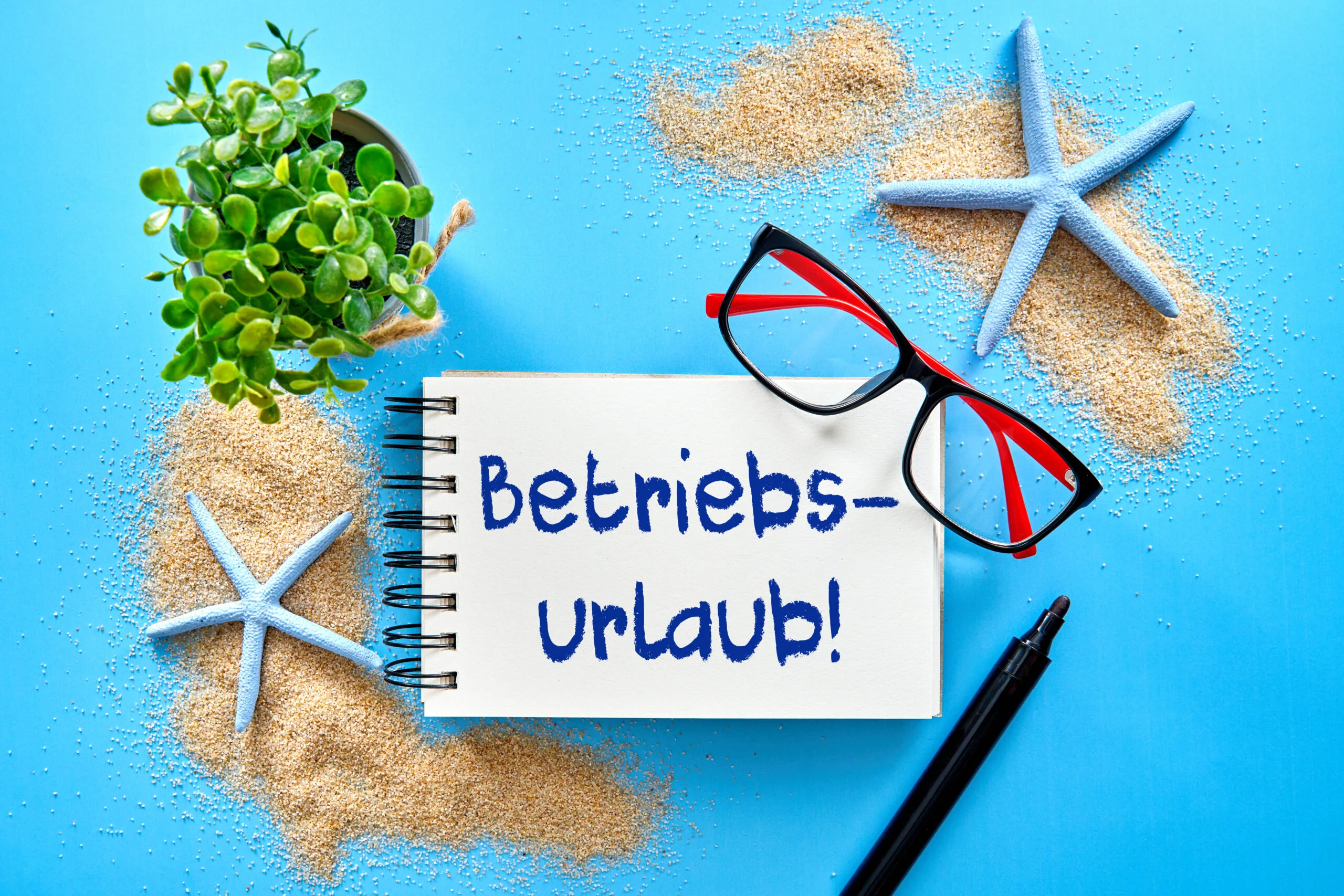 Notizblock mit aufschrift betriebsurlaub neben sonnenbrille und muscheln im sand