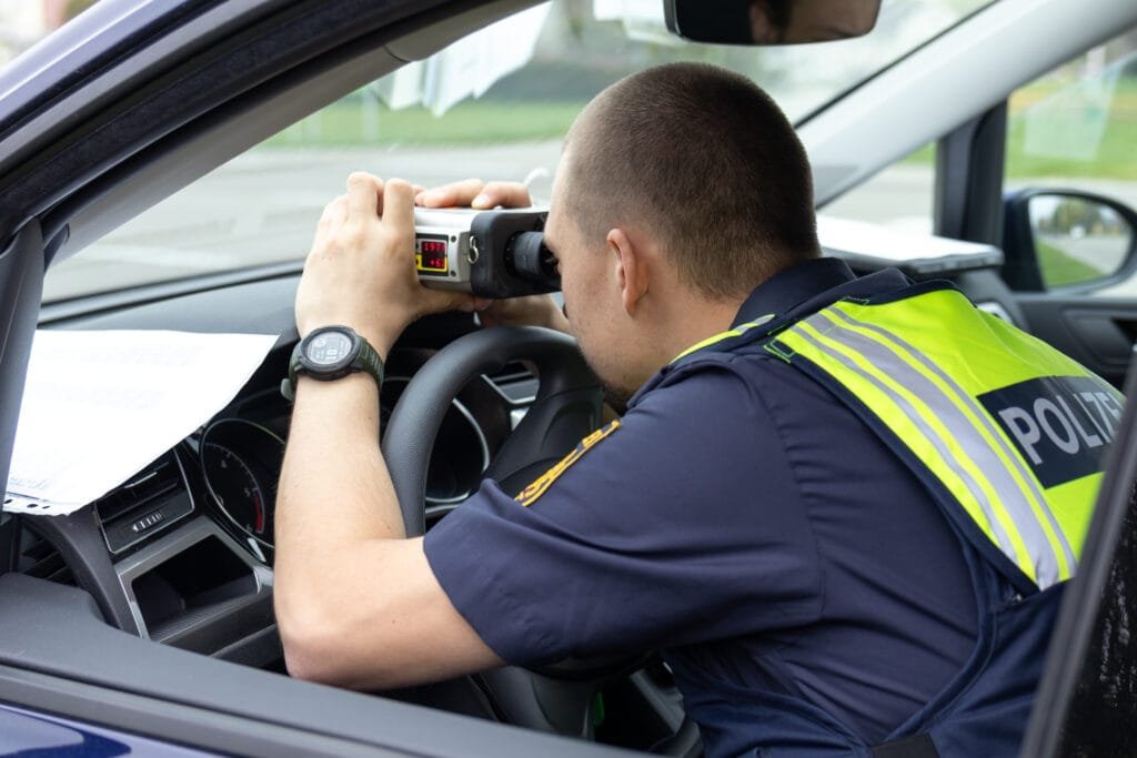 Blitzermarathon 2026: bayern richtet den blick auf gefährliche landstraßen 4 blitzermarathon 2026 Polizist führt eine geschwindigkeitskontrolle mit einer laserpistole aus einem polizeifahrzeug durch