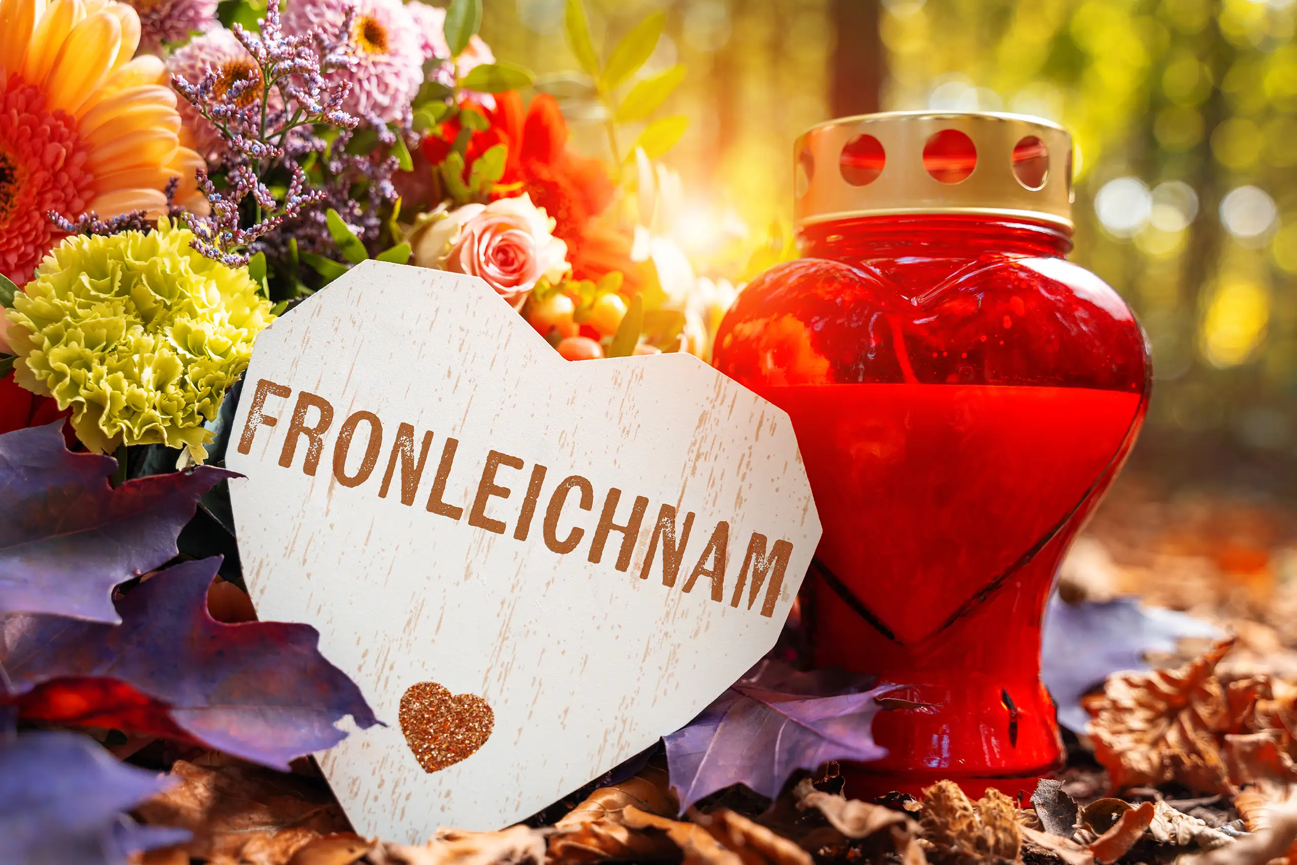 Fronleichnam bild mit roter kerze, blumen und herzschild als religiöses motiv zum katholischen feiertag fronleichnam