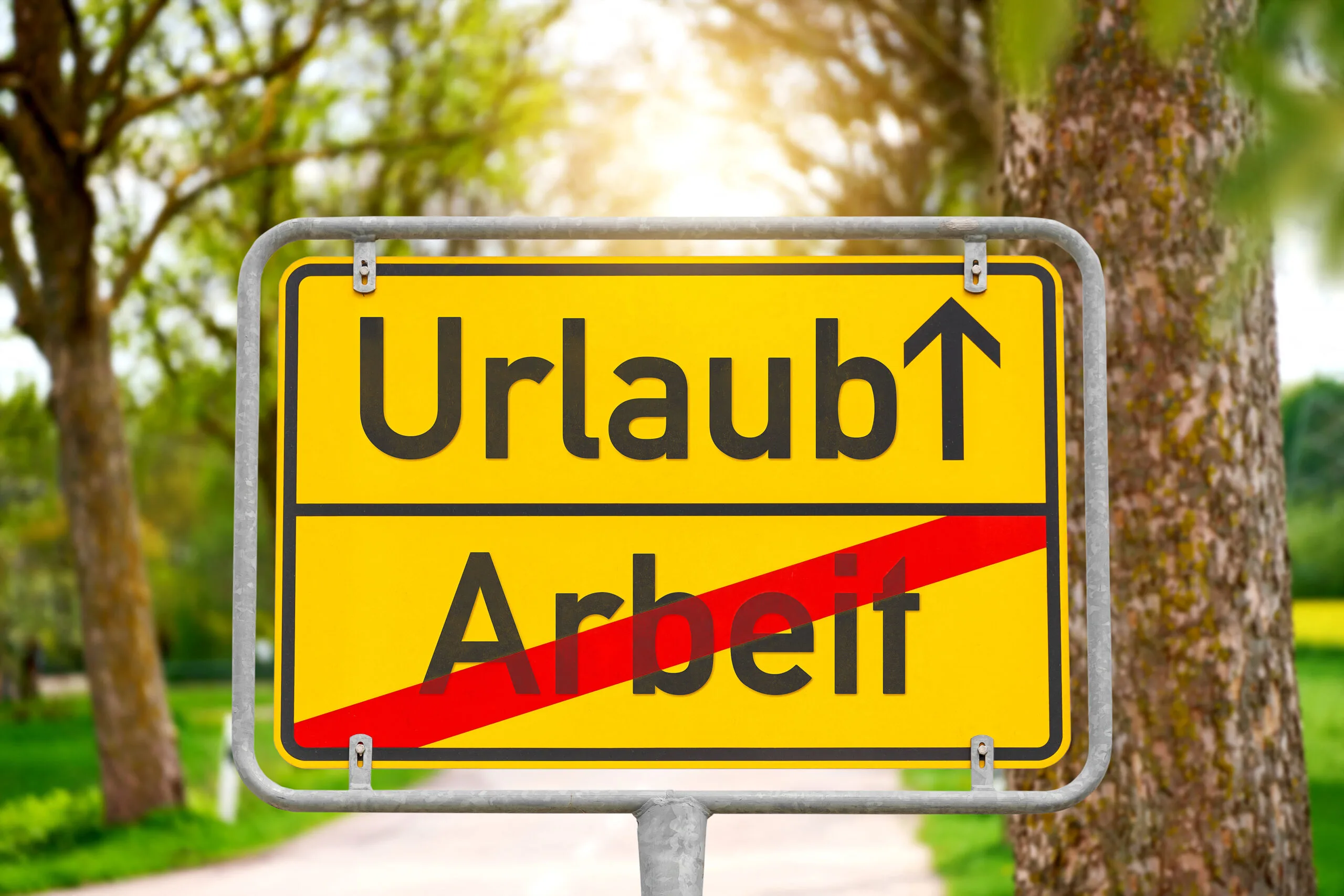 Wegweiser zwischen arbeit und urlaub auf gelbem straßenschild im grünen